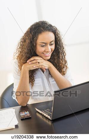 Office worker sitting by desk with laptop View Large Photo Image Stock Photo - Office worker sitting by desk with laptop. Fotosearch