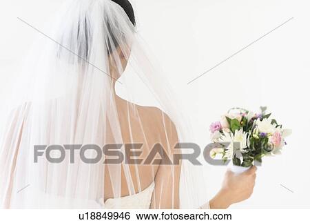 Stock Photograph - Portrait of bride in veil holding bouquet. Fotosearch