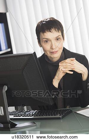 Stock Image - Portrait of businesswoman at desk. Fotosearch