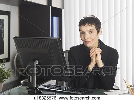 Stock Photograph - Portrait of businesswoman at desk. Fotosearch
