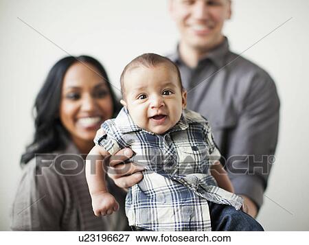 Stock Photo - Portrait of happy multiethnic family with baby boy (2-5 months) on front. Fotosearch