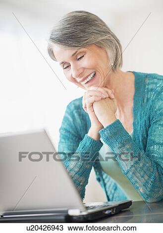 Stock Image - Portrait of happy woman in front of laptop. Fotosearch