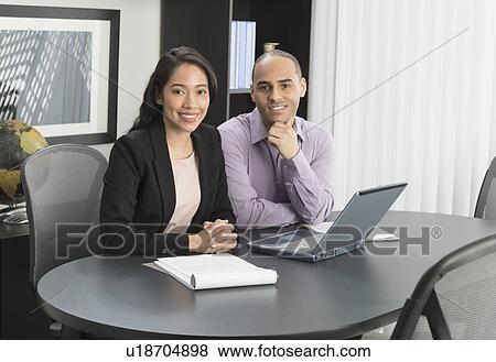 Stock Photo - Portrait of man and woman at meeting in office. Fotosearch
