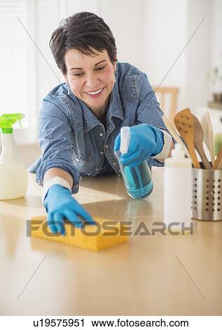 Stock Image - Portrait of mature woman cleaning kitchen. Fotosearch