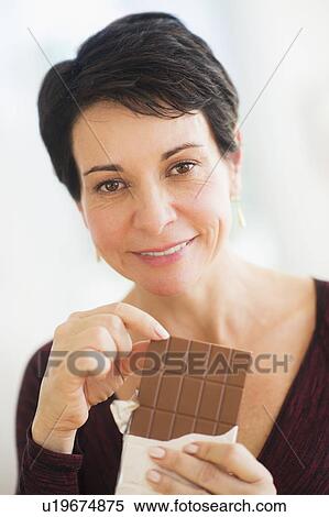 Portrait of mature woman eating chocolate View Large Photo Image Stock Photography - Portrait of mature woman eating chocolate. Fotosearch