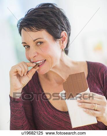 Portrait of mature woman eating chocolate View Large Photo Image Stock Photography - Portrait of mature woman eating chocolate. Fotosearch