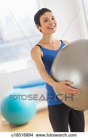 Picture - Portrait of mature woman exercising in gym. Fotosearch
