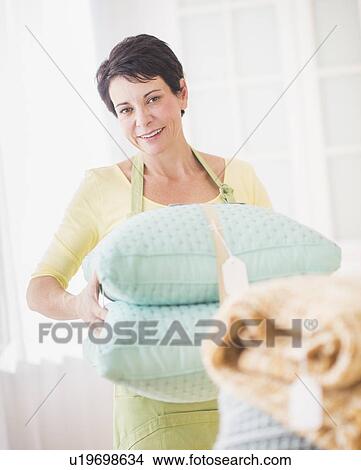 Picture - Portrait of mature woman holding pillows. Fotosearch
