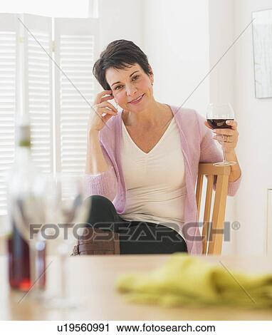 Stock Image - Portrait of mature woman holding wine glass. Fotosearch