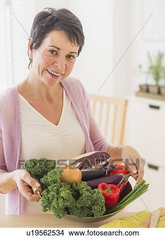Portrait of mature woman holding wok with vegetables View Large Photo Image Picture - Portrait of mature woman holding wok with vegetables. Fotosearch