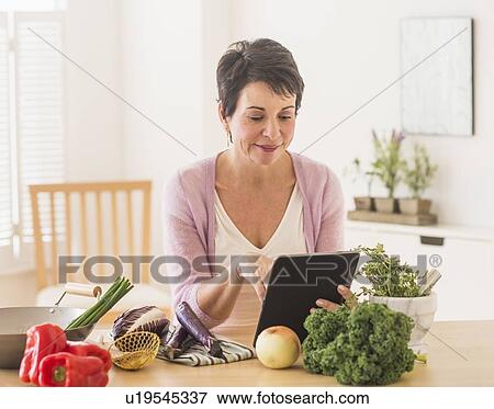 Stock Photo - Portrait of mature woman in kitchen. Fotosearch