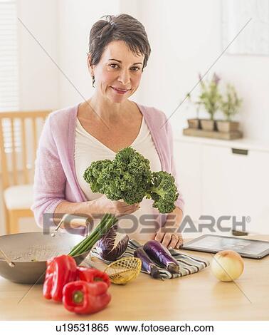 Stock Photography - Portrait of mature woman in kitchen. Fotosearch
