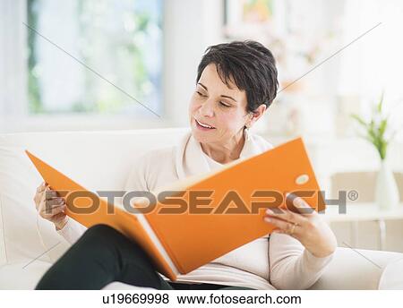 Stock Photo - Portrait of mature woman looking at photo album. Fotosearch
