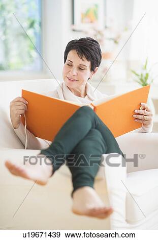 Stock Photo - Portrait of mature woman looking at photo album. Fotosearch
