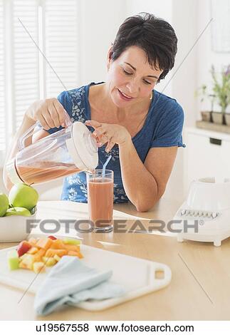 Portrait of mature woman pouring glass of smoothie from blender View Large Photo Image Stock Photo - Portrait of mature woman pouring glass of smoothie from blender. Fotosearch