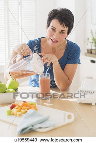 Portrait of mature woman pouring glass of smoothie from blender View Large Photo Image Stock Photo - Portrait of mature woman pouring glass of smoothie from blender. Fotosearch