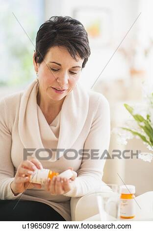 Stock Image - Portrait of mature woman taking pills. Fotosearch