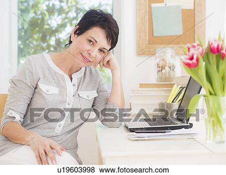 Stock Photo - Portrait of mature woman using laptop. Fotosearch