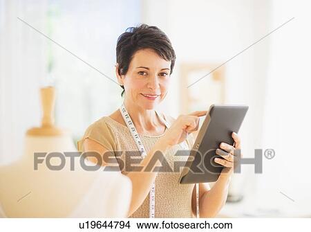 Picture - Portrait of mature woman with clothing bust using digital tablet. Fotosearch