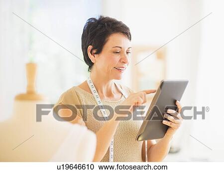 Stock Image - Portrait of mature woman with clothing bust using digital tablet. Fotosearch