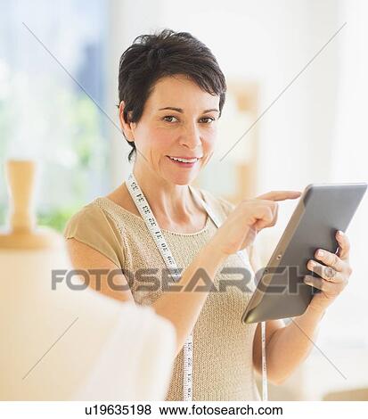 Stock Photo - Portrait of mature woman with clothing bust using digital tablet. Fotosearch