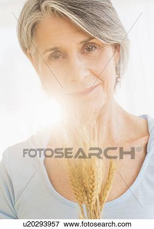 Stock Photo - Portrait of pensive woman holding dry wheat. Fotosearch