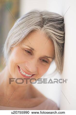 Stock Image - Portrait of relaxed woman leaning against wall. Fotosearch