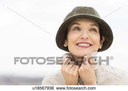Portrait of smiling woman wearing raincoat and hat View Large Photo Image Stock Photo - Portrait of smiling woman wearing raincoat and hat. Fotosearch