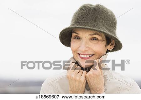 Portrait of smiling woman wearing raincoat and hat View Large Photo Image Stock Photo - Portrait of smiling woman wearing raincoat and hat. Fotosearch