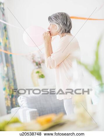 Stock Photo - Portrait of woman blowing balloon. Fotosearch