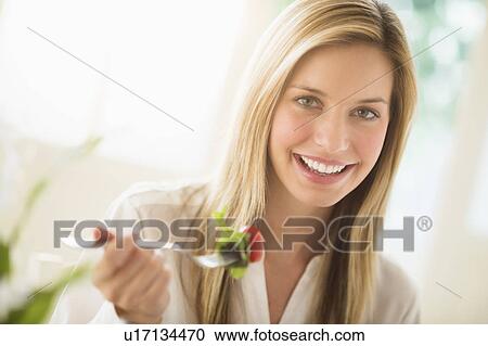 Stock Image - Portrait of woman eating and smiling. Fotosearch