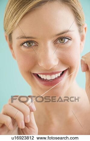 Stock Image - Portrait of woman flossing teeth. Fotosearch