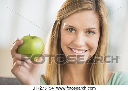 Picture - Portrait of woman holding apple. Fotosearch