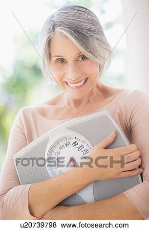 Portrait of woman holding bathroom scale View Large Photo Image Stock Photo - Portrait of woman holding bathroom scale. Fotosearch