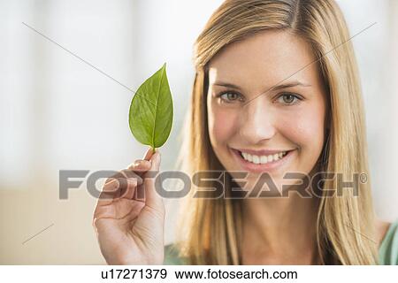 Stock Photo - Portrait of woman holding leaf. Fotosearch