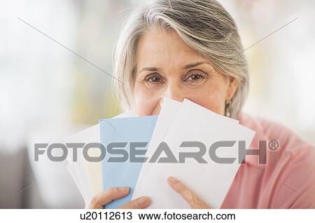 Stock Image - Portrait of woman holding mail. Fotosearch