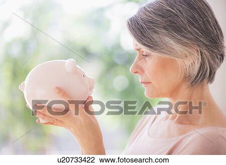 Stock Image - Portrait of woman holding piggy bank. Fotosearch