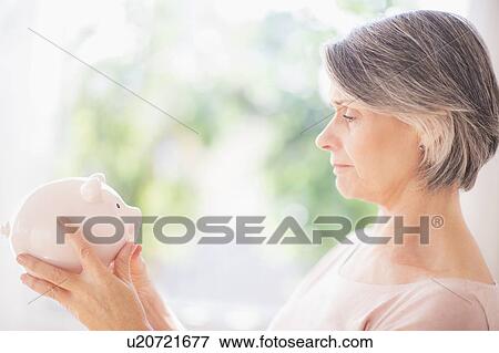 Stock Photo - Portrait of woman holding piggy bank. Fotosearch