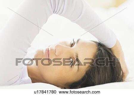 Stock Image - Portrait of woman lying in bed. Fotosearch