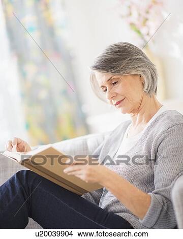Picture - Portrait of woman reading on sofa. Fotosearch
