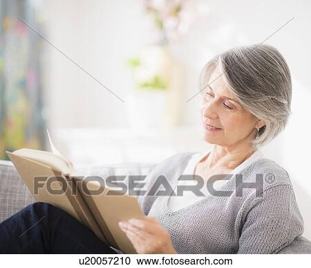 Stock Image - Portrait of woman reading on sofa. Fotosearch