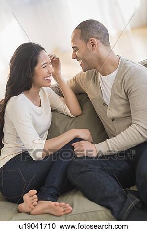 Portrait of young couple sitting on couch View Large Photo Image Stock Image - Portrait of young couple sitting on couch. Fotosearch
