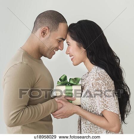 Stock Photo - Portrait of young couple with anniversary present. Fotosearch