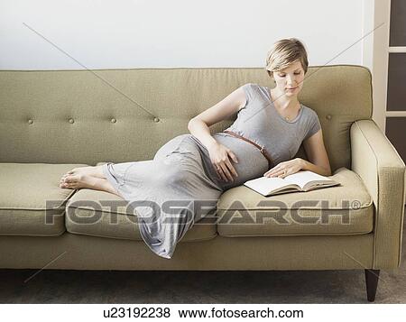 Pregnant woman lying on sofa reading View Large Photo Image Stock Photo - Pregnant woman lying on sofa reading. Fotosearch