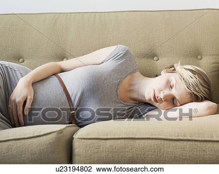 Stock Image - Pregnant woman lying on sofa sleeping. Fotosearch