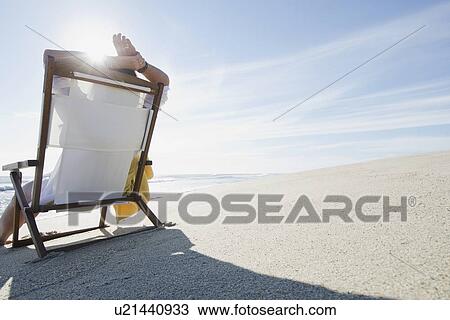 Rear view of woman relaxing on chair at beach View Large Photo Image Stock Image - Rear view of woman relaxing on chair at beach. Fotosearch