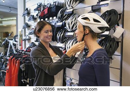 Sales clerk helping to choose cycling helmet to customer View Large Photo Image Stock Photograph - Sales clerk helping to choose cycling helmet to customer. Fotosearch