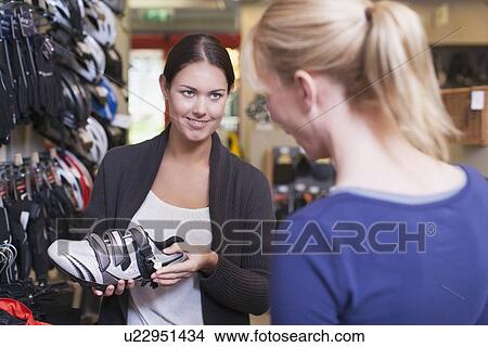 Sales clerk showing sports shoes to customer View Large Photo Image Picture - Sales clerk showing sports shoes to customer. Fotosearch