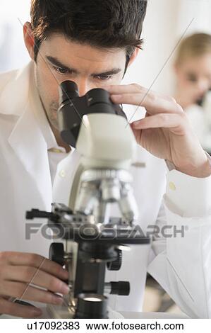 Stock Image - Scientist doing research on microscopes. Fotosearch