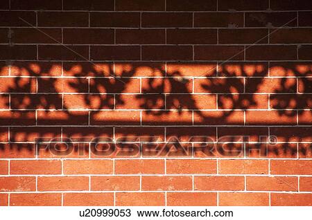 Stock Image - Shadow of railing on brick wall. Fotosearch